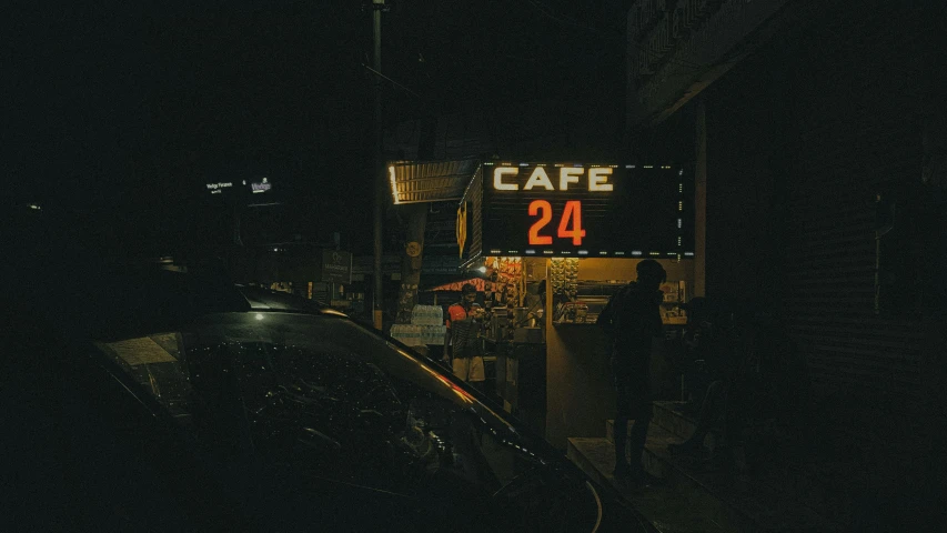 a dark street at night with a cafe sign