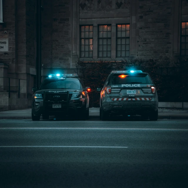 two police cars parked on the side of a city street at night