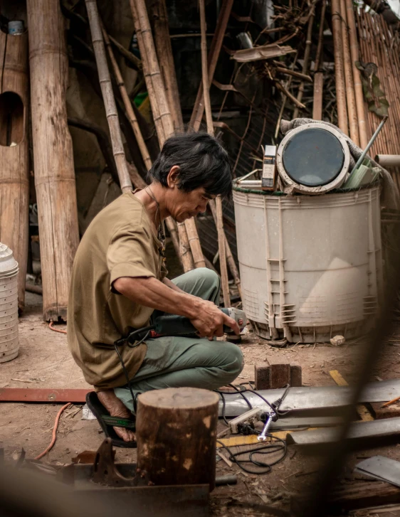 a man sitting in front of a gas tank next to a metal object