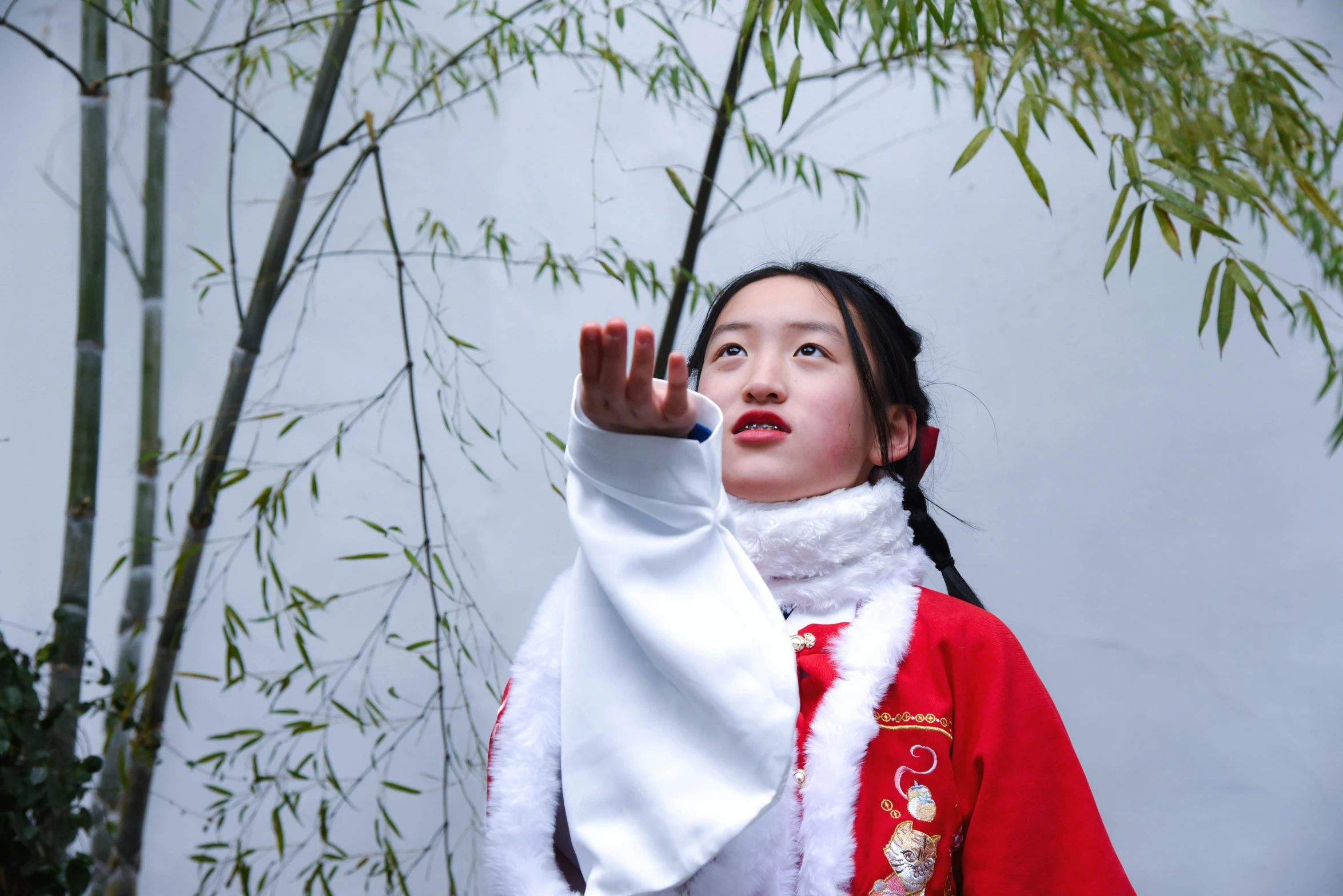 a woman dressed in chinese clothing reaching up with her hand to grab soing