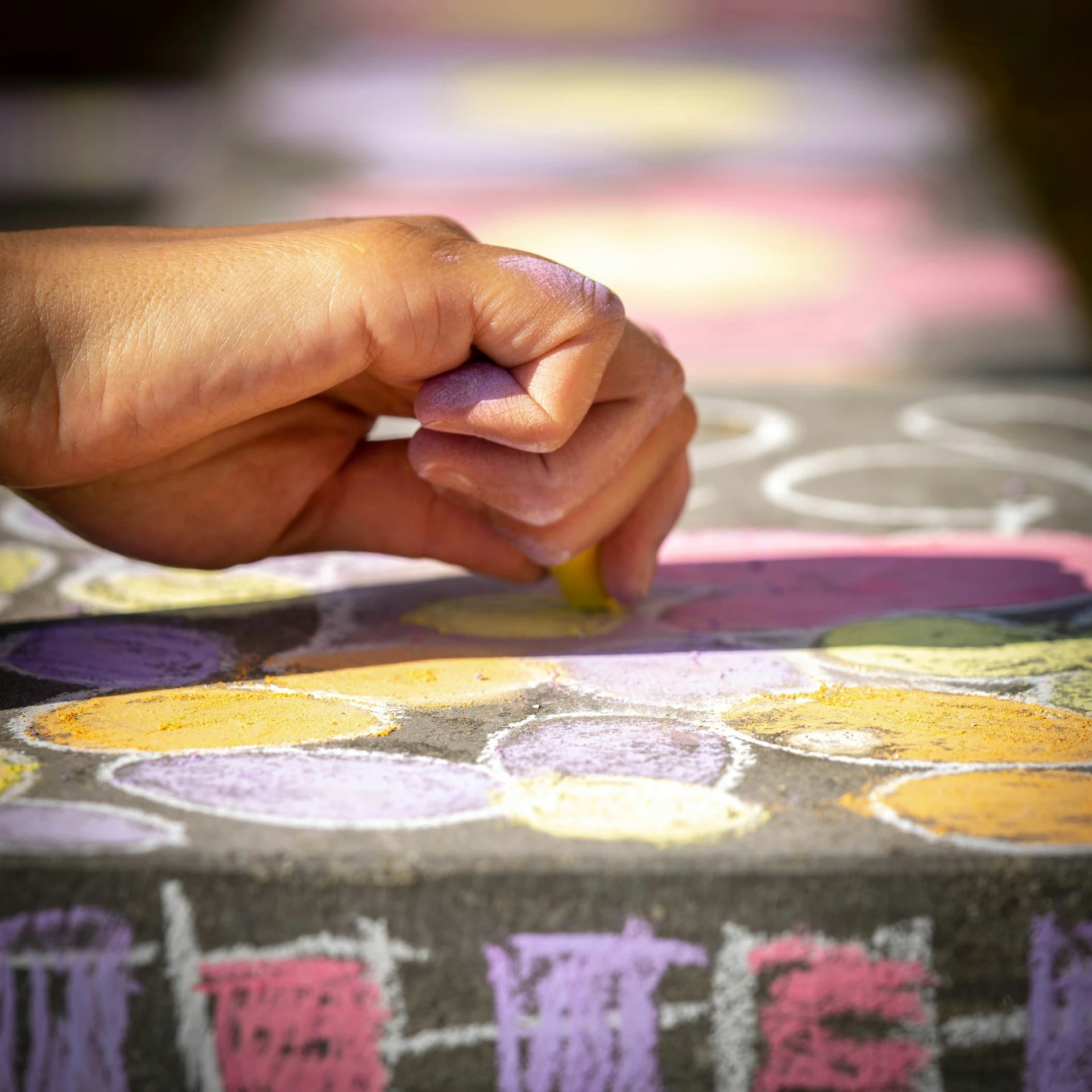 a hand writing with a pencil on top of a patterned tablecloth