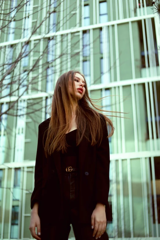 woman with long brown hair standing outside a tall building