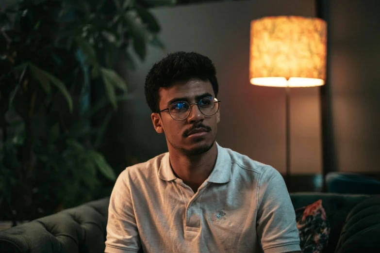 a man sitting in front of a lamp with glasses