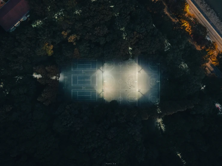 aerial view of tennis court, street lights and trees