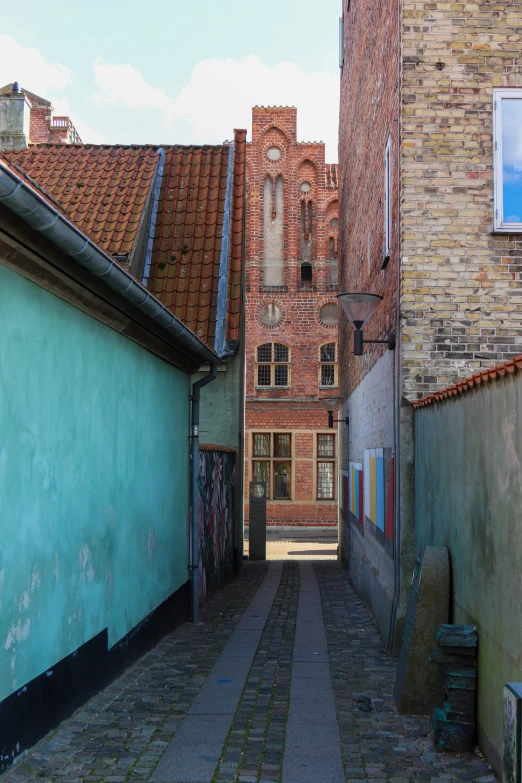 an alley with a clock tower and a red brick building