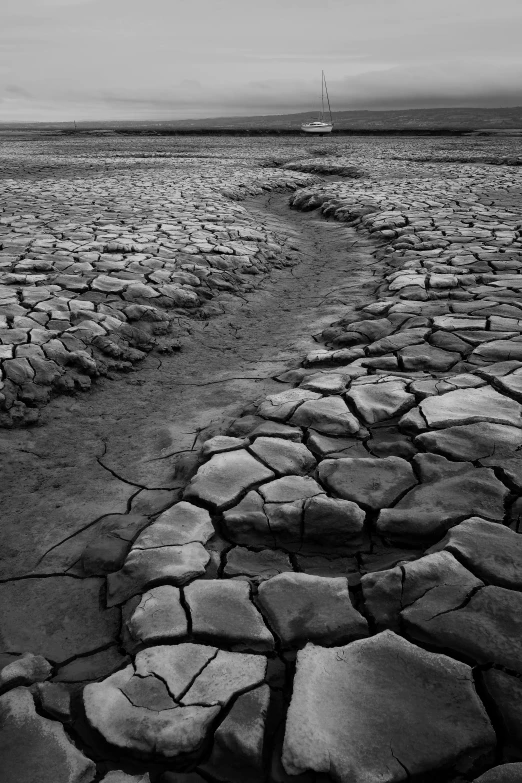 landscape po of a field with dry rocks and a boat in the distance