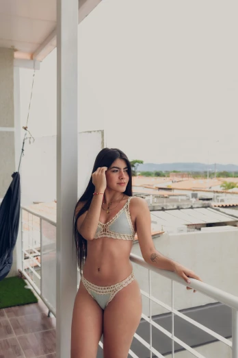 a beautiful woman wearing a bikini top posing by a wall