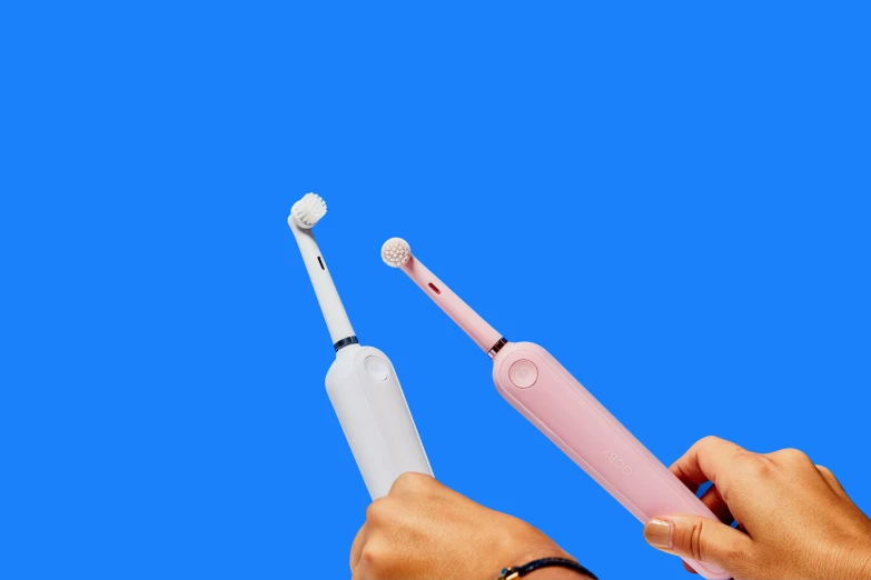 a person holding up a pink and white electric toothbrush