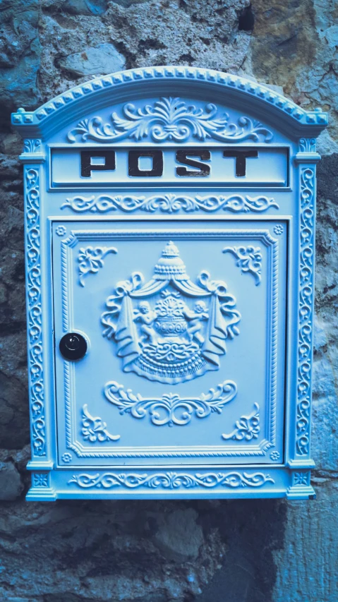 a large blue post box sitting on top of a stone wall