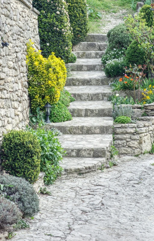 a stone house with stone stairs and bushes surrounding it