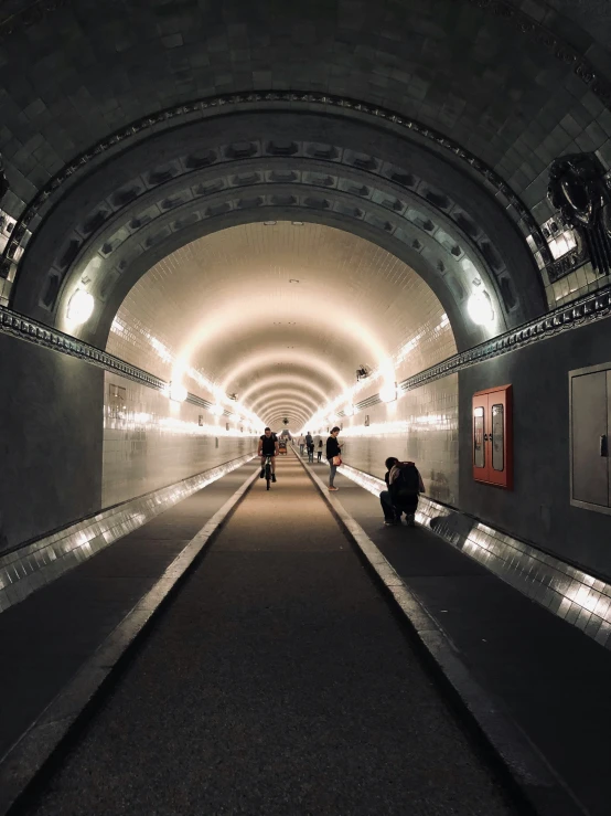 two people are sitting on the ground in a very long tunnel