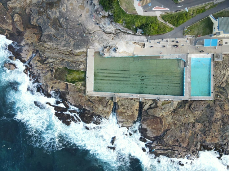 an aerial view of an outdoor swimming pool on a cliff near the water