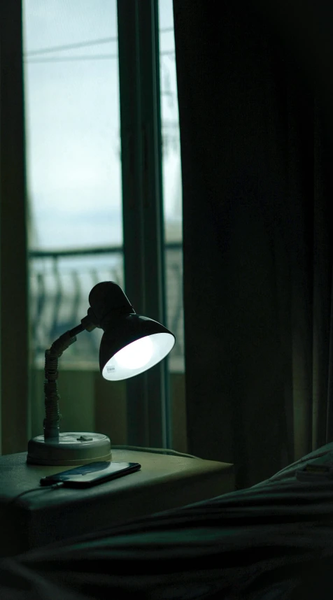 a table lamp next to a window in the dark