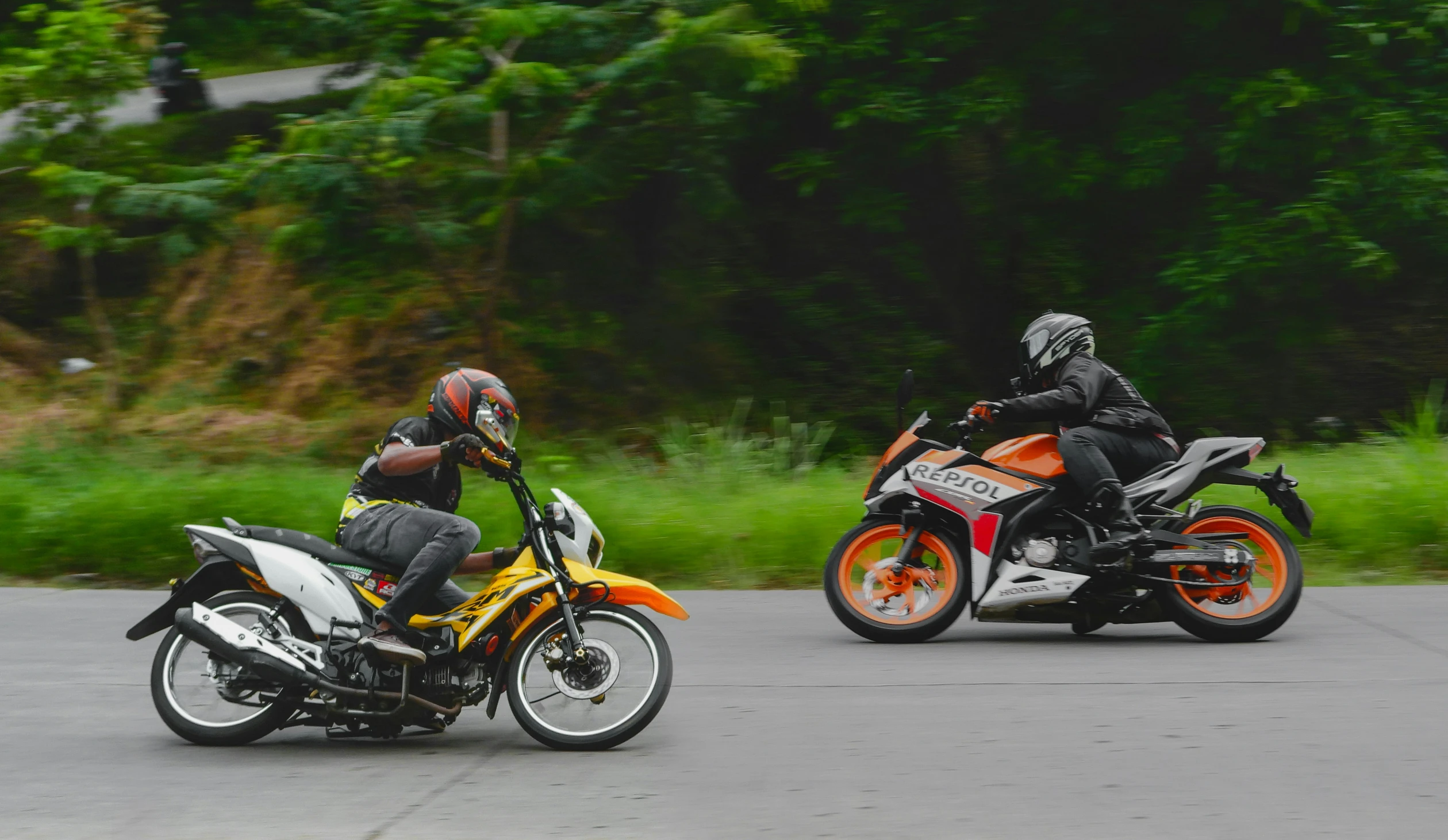two men riding motorcycles down a winding road