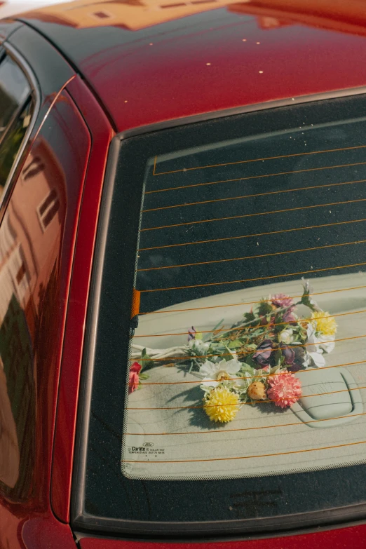 the reflection in a parked car of flowers and some sort of fabric