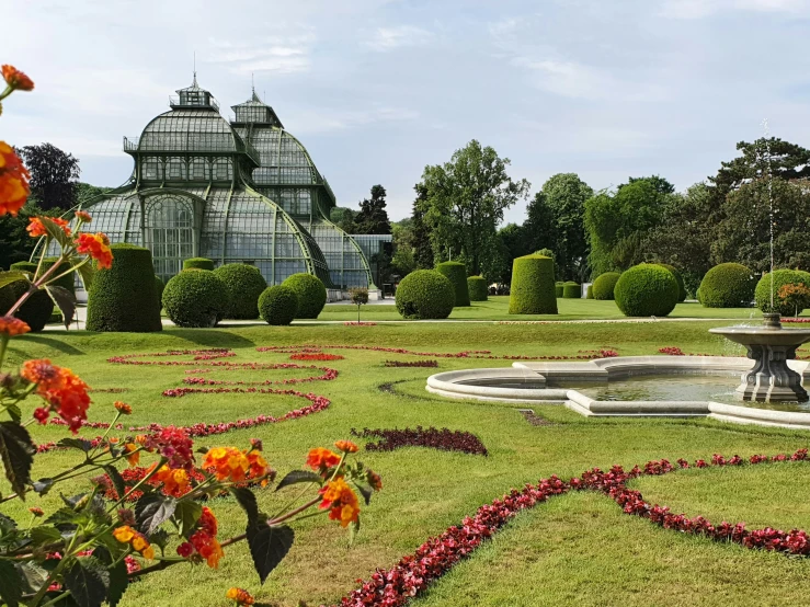 an ornate park with a fountain and flower arrangements in the center