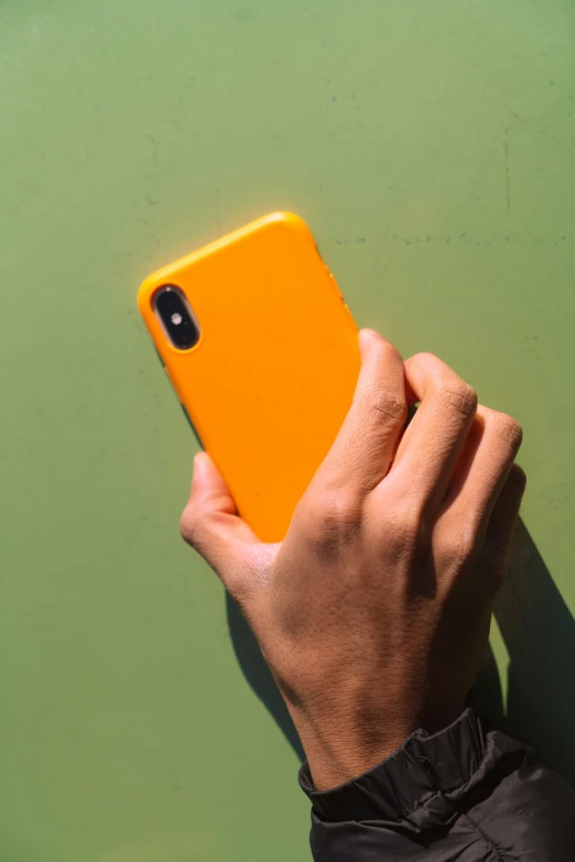 a person holding a yellow phone while wearing sunglasses