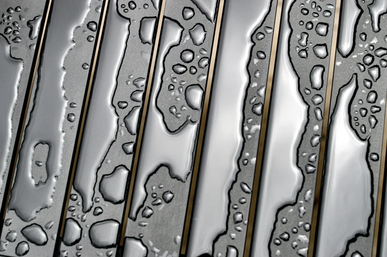 several different drops of water on the side of a metal bench