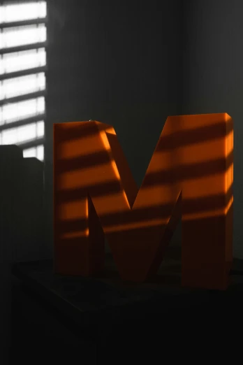 the letter m is sitting in front of a window