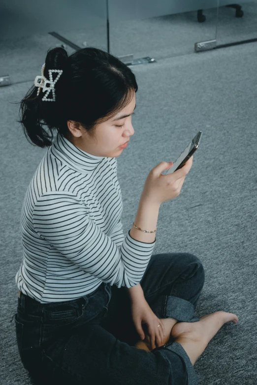 a young woman is sitting on the ground texting