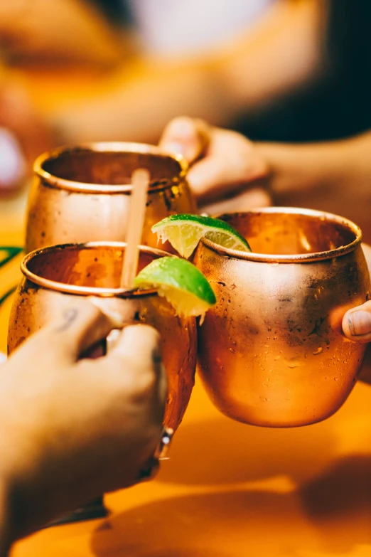 three people are holding ss cups with lime leaves