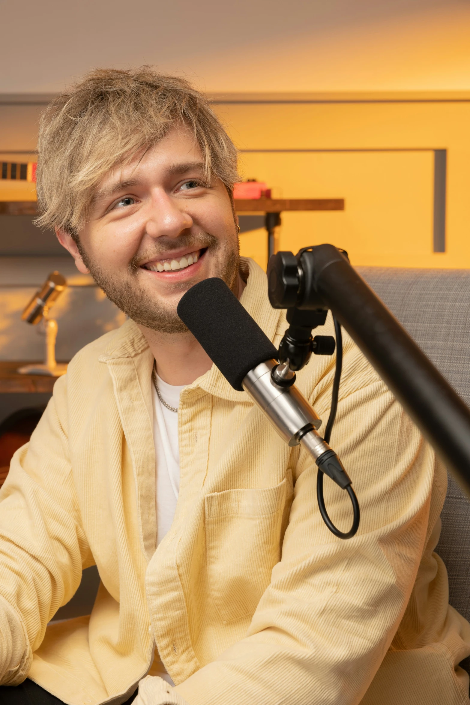 the smiling man sits in front of a microphone