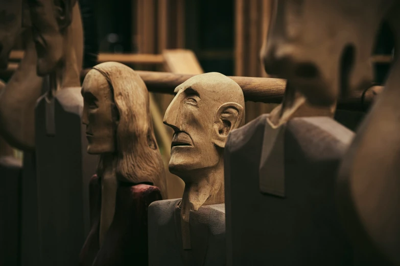 multiple wooden sculptures of people are placed on wooden shelves