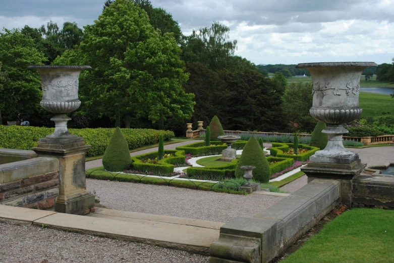 there are many plants in the garden near large urns