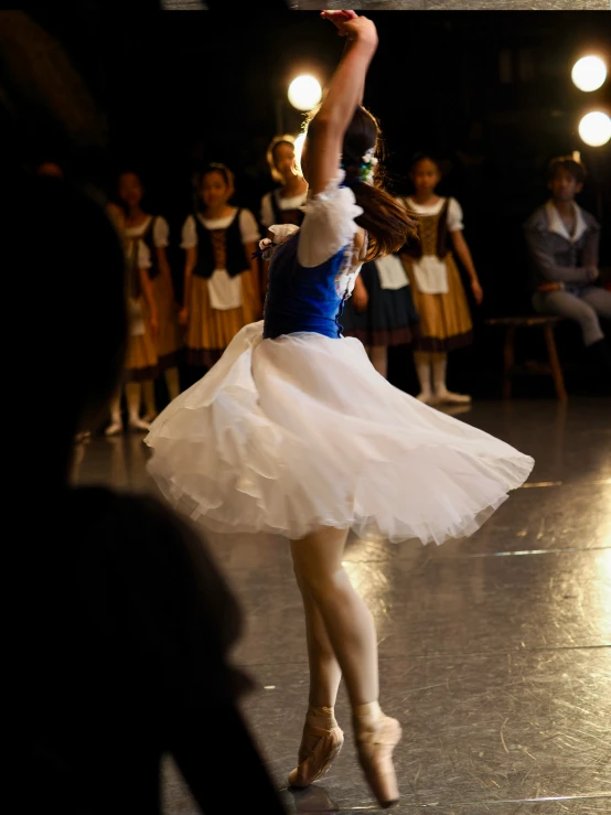 a female dancer dressed in white performs with other dancers
