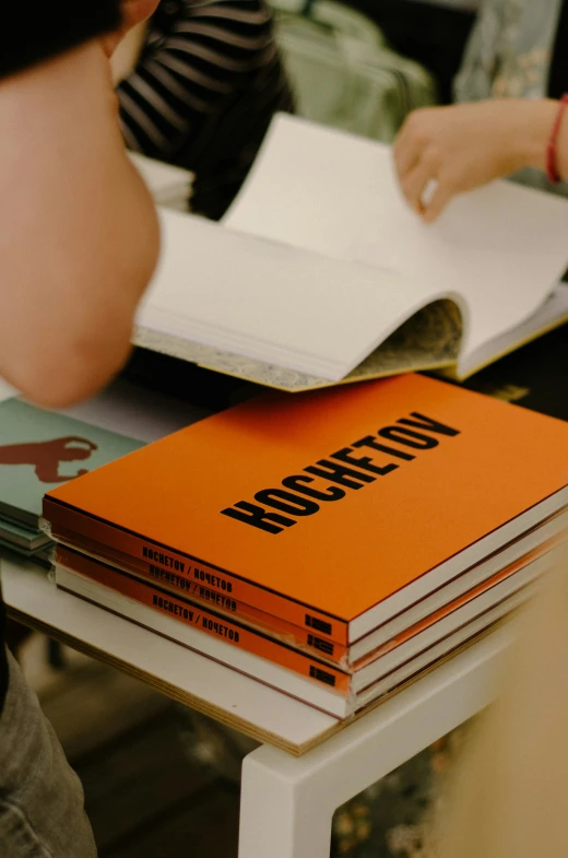 two people sitting at a table with books