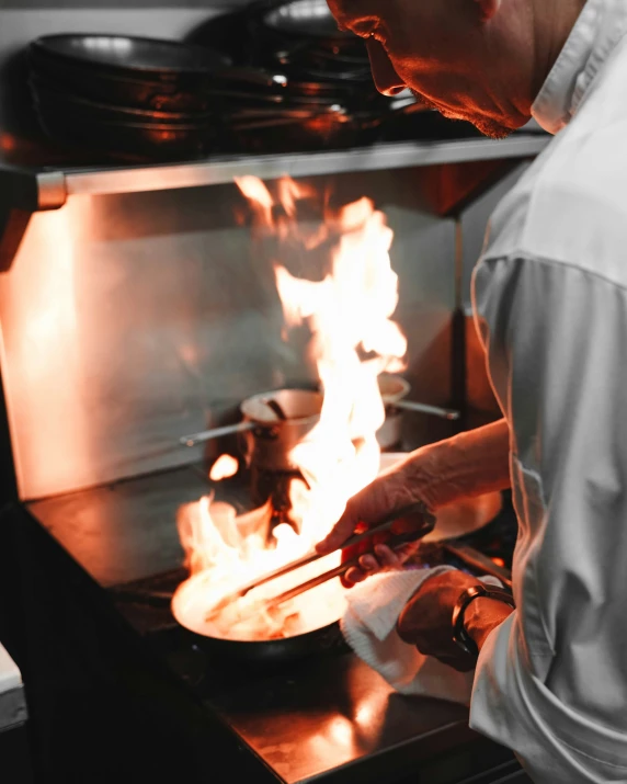 a man cooking with flames behind an oven