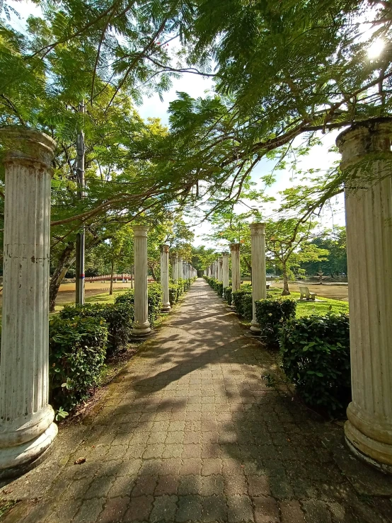 a stone path with a brick walkway between two white columns