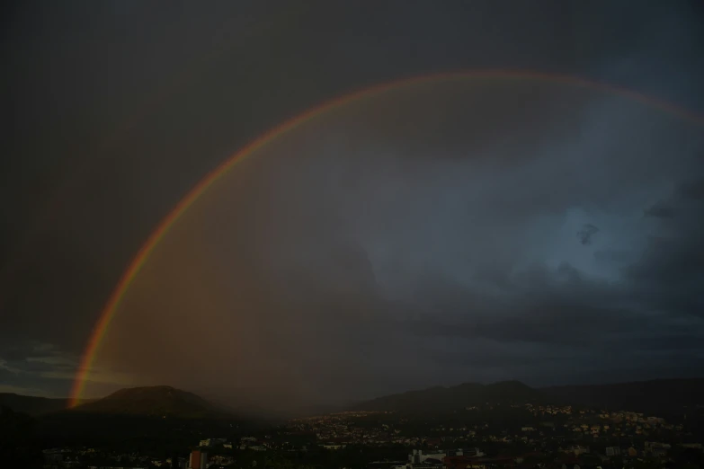 there is a rainbow in the sky and a boat sailing by