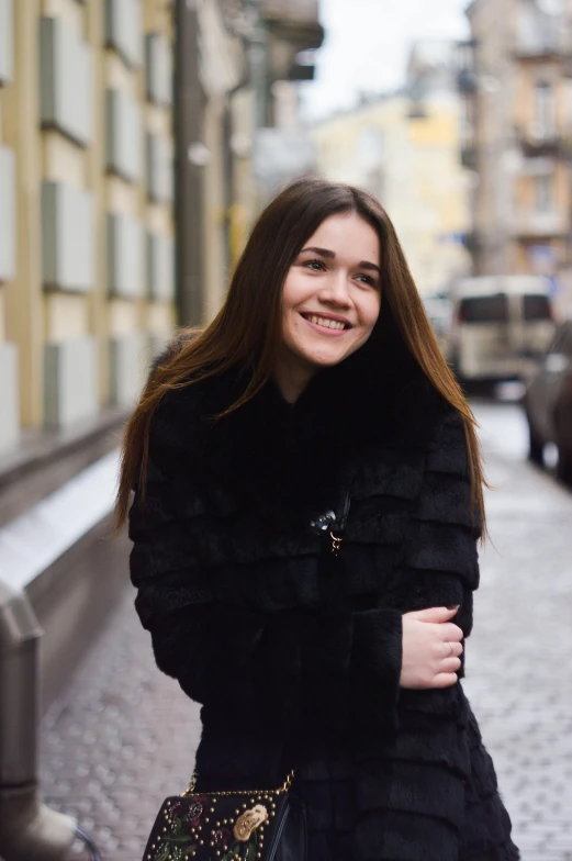 a smiling woman stands by the curb and smiles at the camera