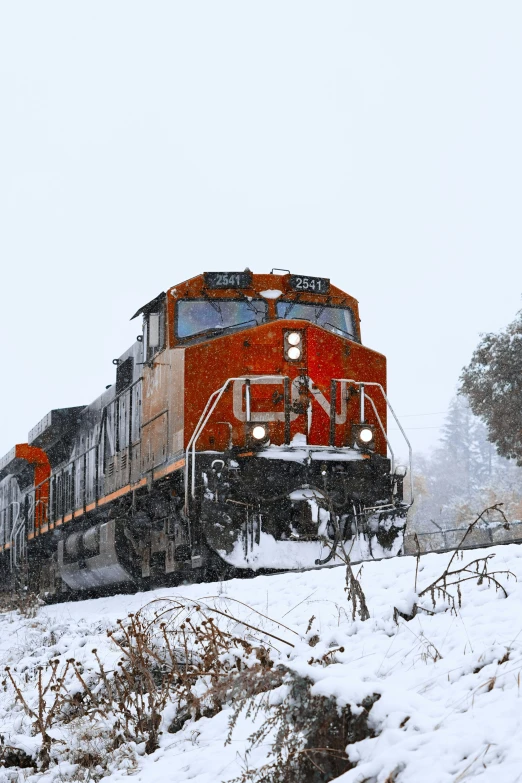 a red train drives down tracks through snow