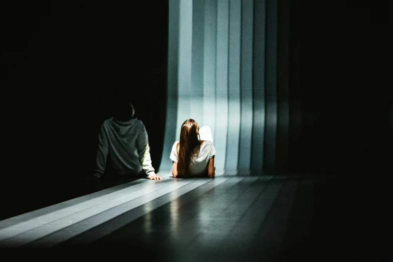 a woman sitting on the floor in front of a curtain