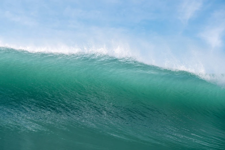 a large wave breaks into the air in front of a blue sky