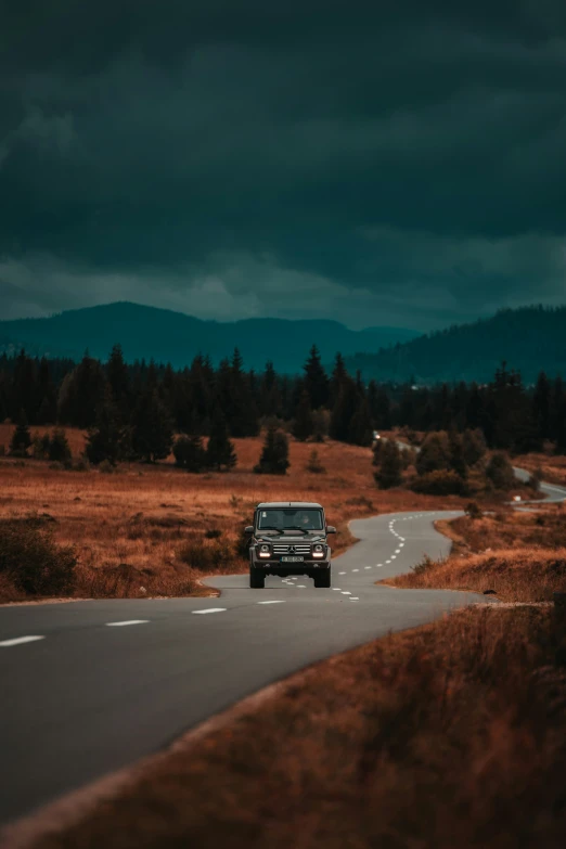 a truck driving down the road in a storm filled forest