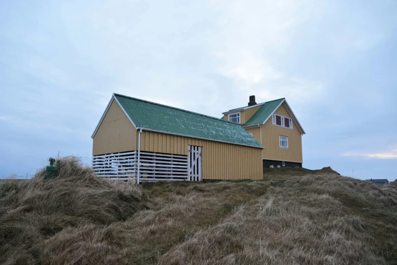 a barn is sitting on a hill top with a fence