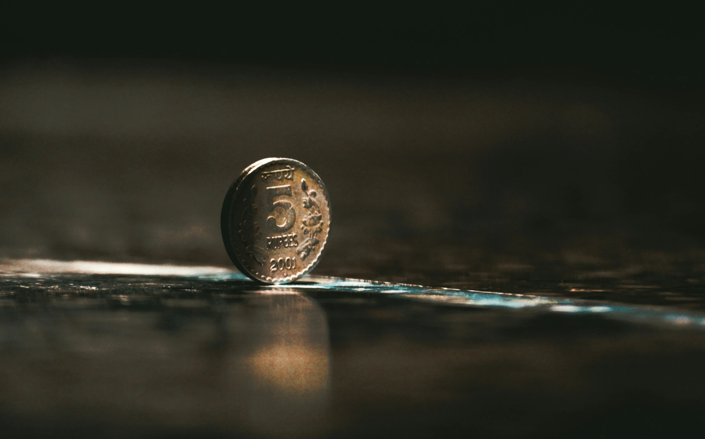 a gold coin laying on a shiny surface