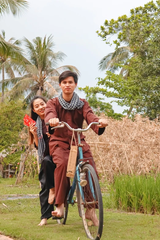 a man and woman riding on the back of a bicycle