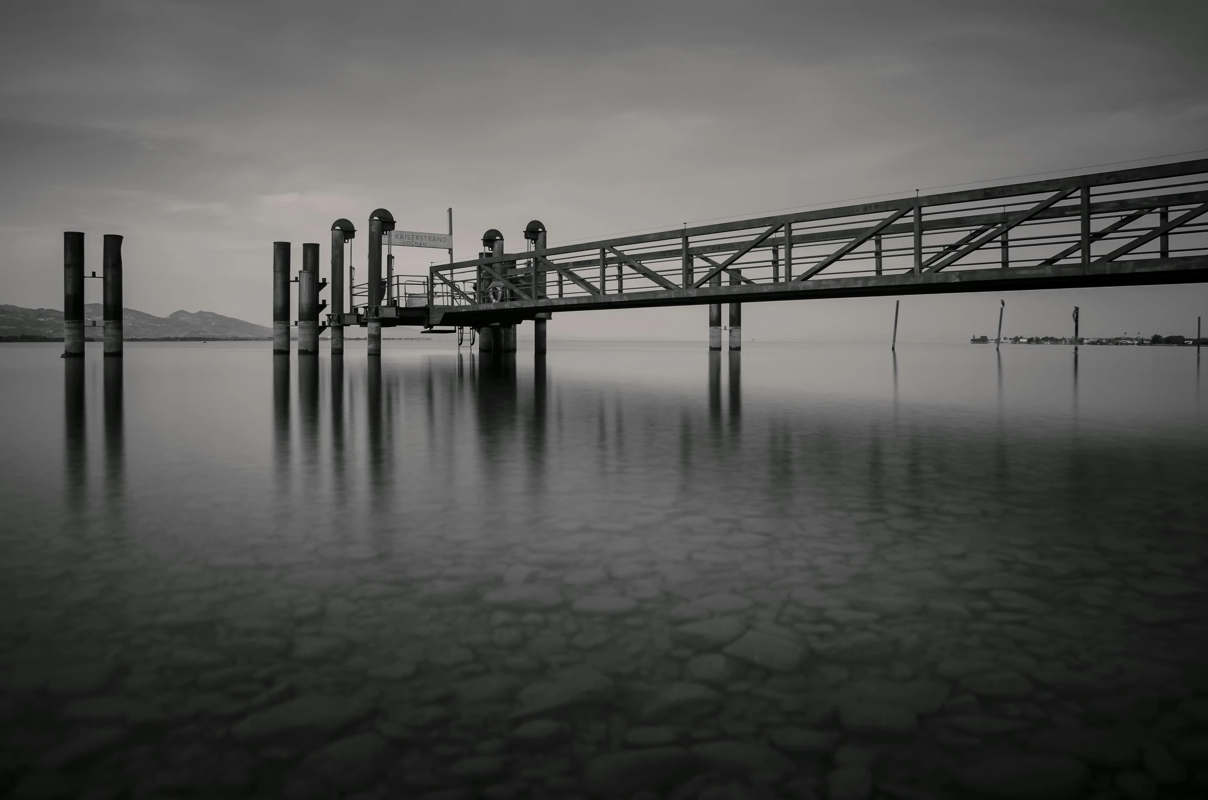 an old wooden bridge over water with a cloudy sky above