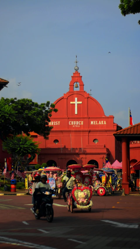 red building with white cross on it and people riding motorbikes