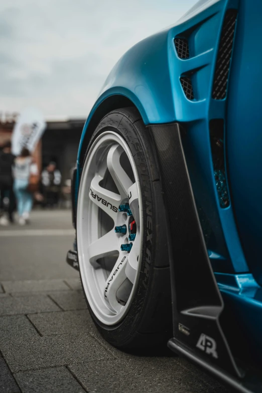 closeup of an unique bmw sport car wheel, with some people watching