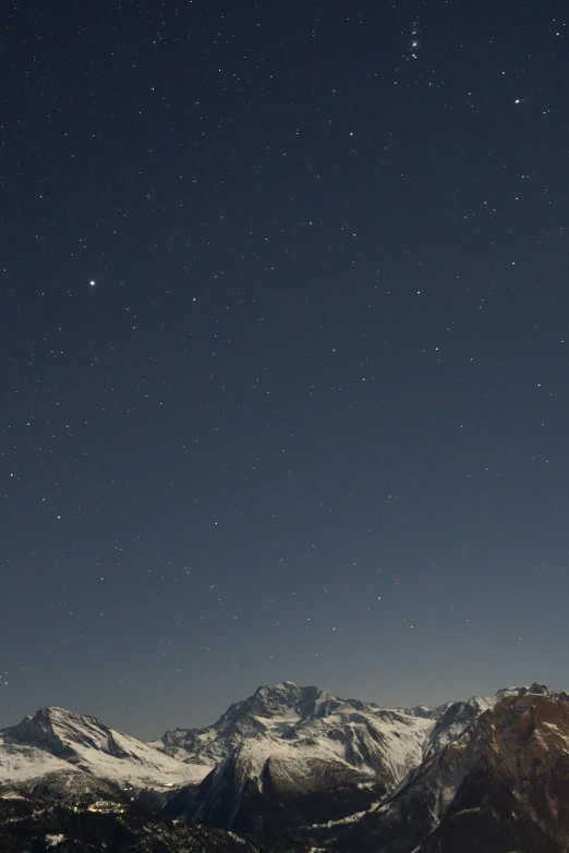 a dark sky filled with clouds and a star covered mountain in the distance