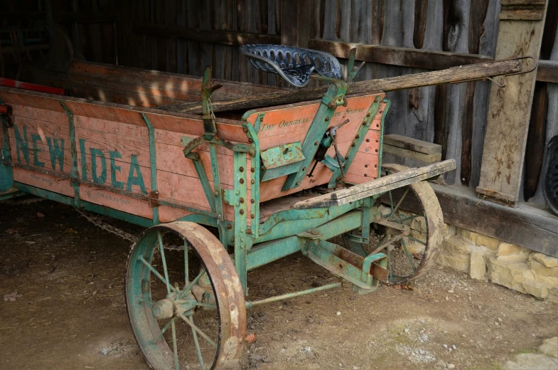 a large rusty wooden wagon sits in a barn