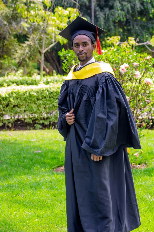 a man in his graduation gown is standing in the park