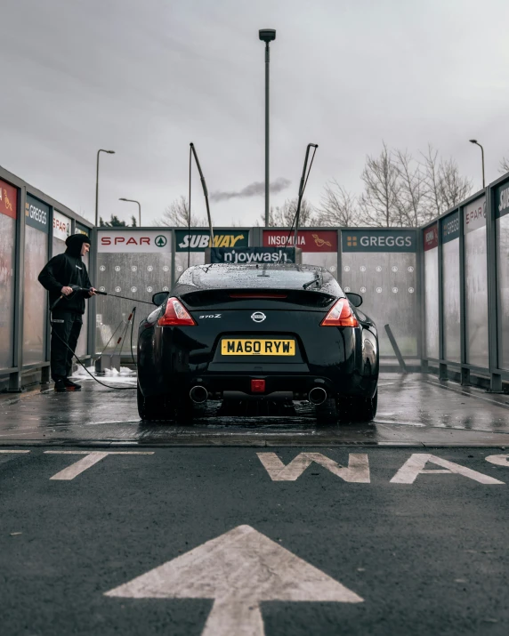 the man is washing off his sports car