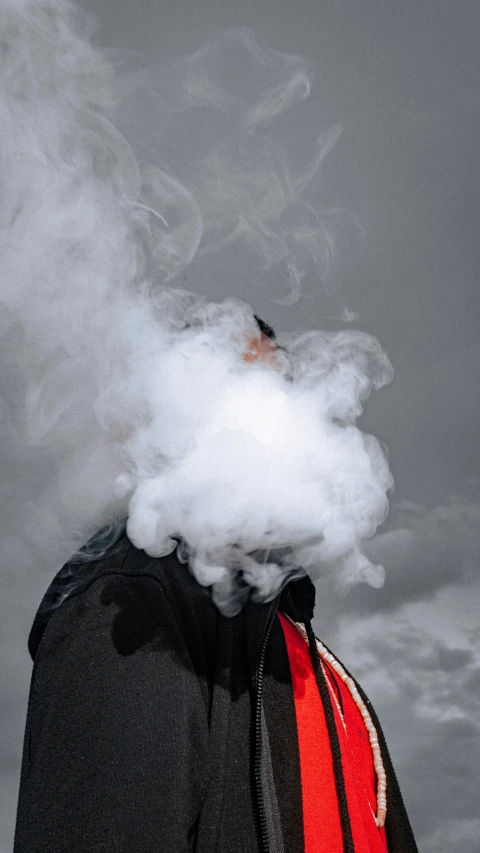 a person in a hoodie emits smoke in the sky
