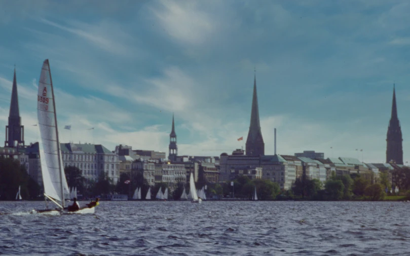 a boat with sail is sailing in front of the city